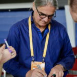 Coach Michael Muench in einem dunkelblauen Hemd schreibt etwas auf eine hellblaue Karte.